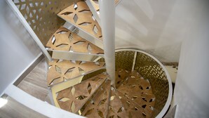 Una scala a chiocciola con motivi geometrici in legno e pareti bianche.