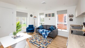 A modern living room with a sofa, a coffee table, and a dining area.