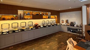 A modern kitchen with a long counter, built-in appliances, and a wooden floor. - SWARNA HOTEL & RESORT (Kanthi)