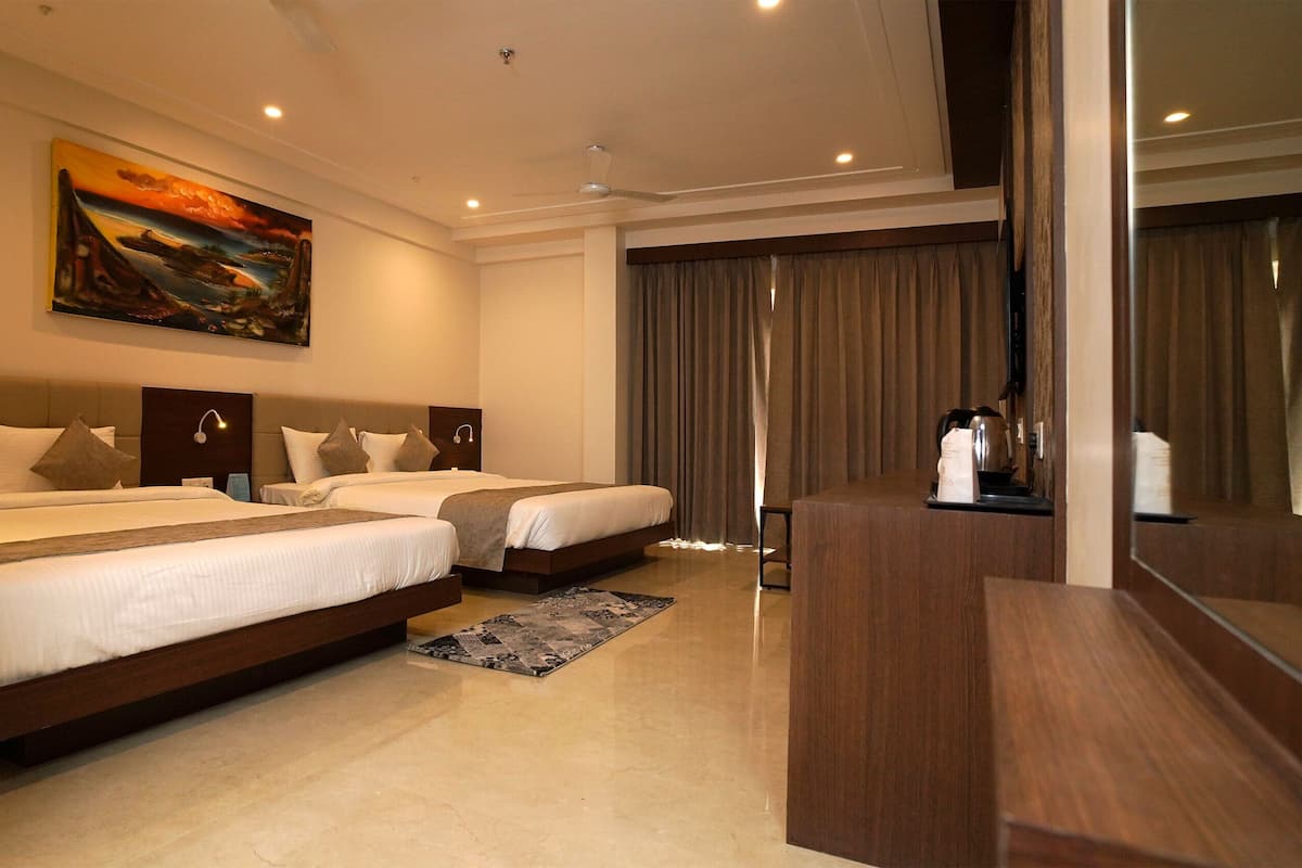 A hotel room with two beds, a desk, a painting, and a large window with curtains.