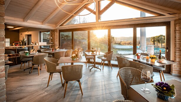 Un comedor amplio con mobiliario de mimbre, ventanas grandes y vistas al exterior.