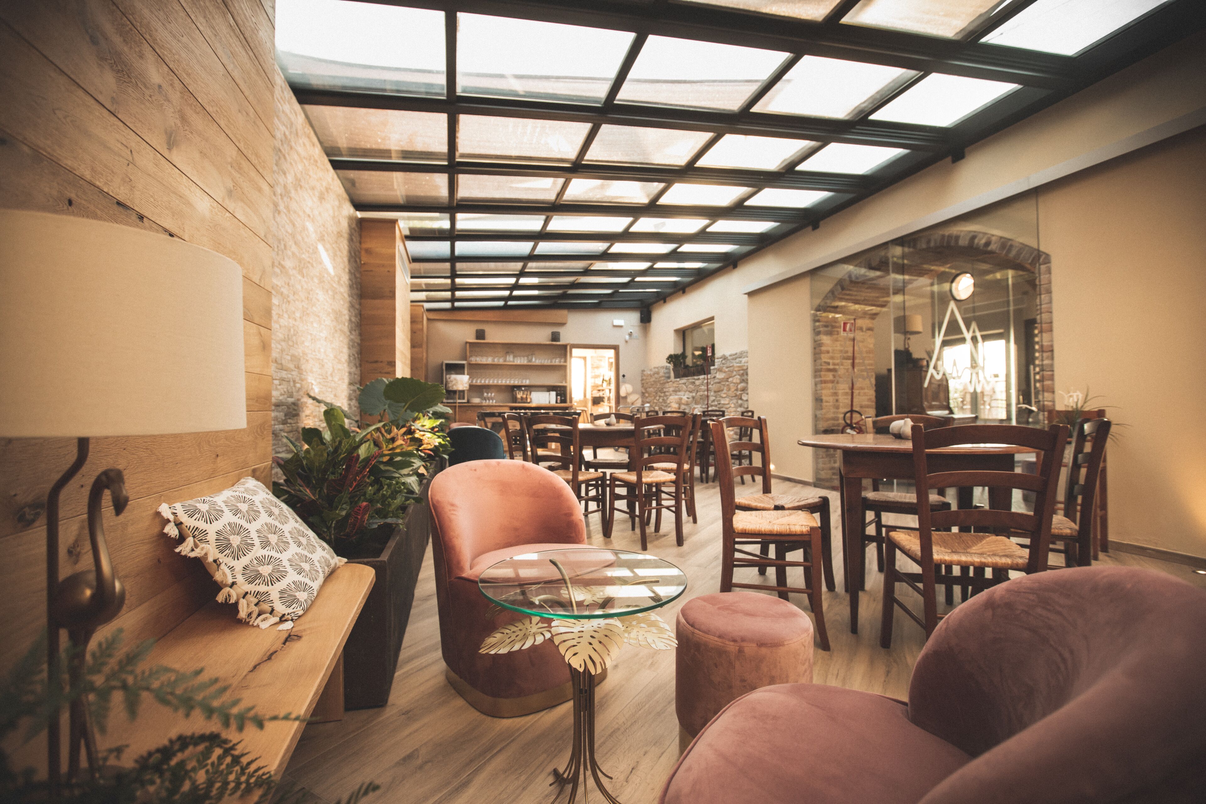 An interior with a wooden bench, a glass table, and a dining area with chairs and a table.