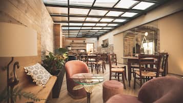 An interior with a wooden bench, a glass table, and a dining area with chairs and a table.