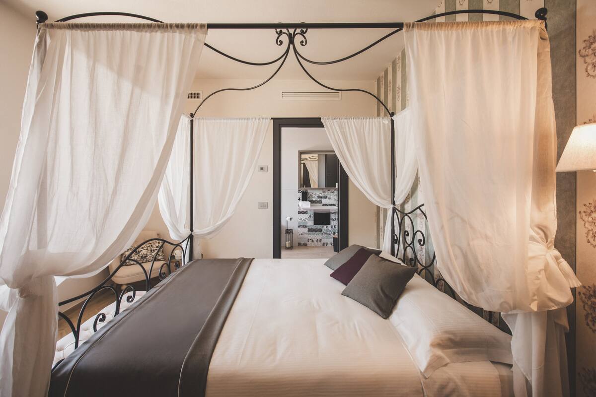 A four-poster canopy bed with white linens and a dark headboard.