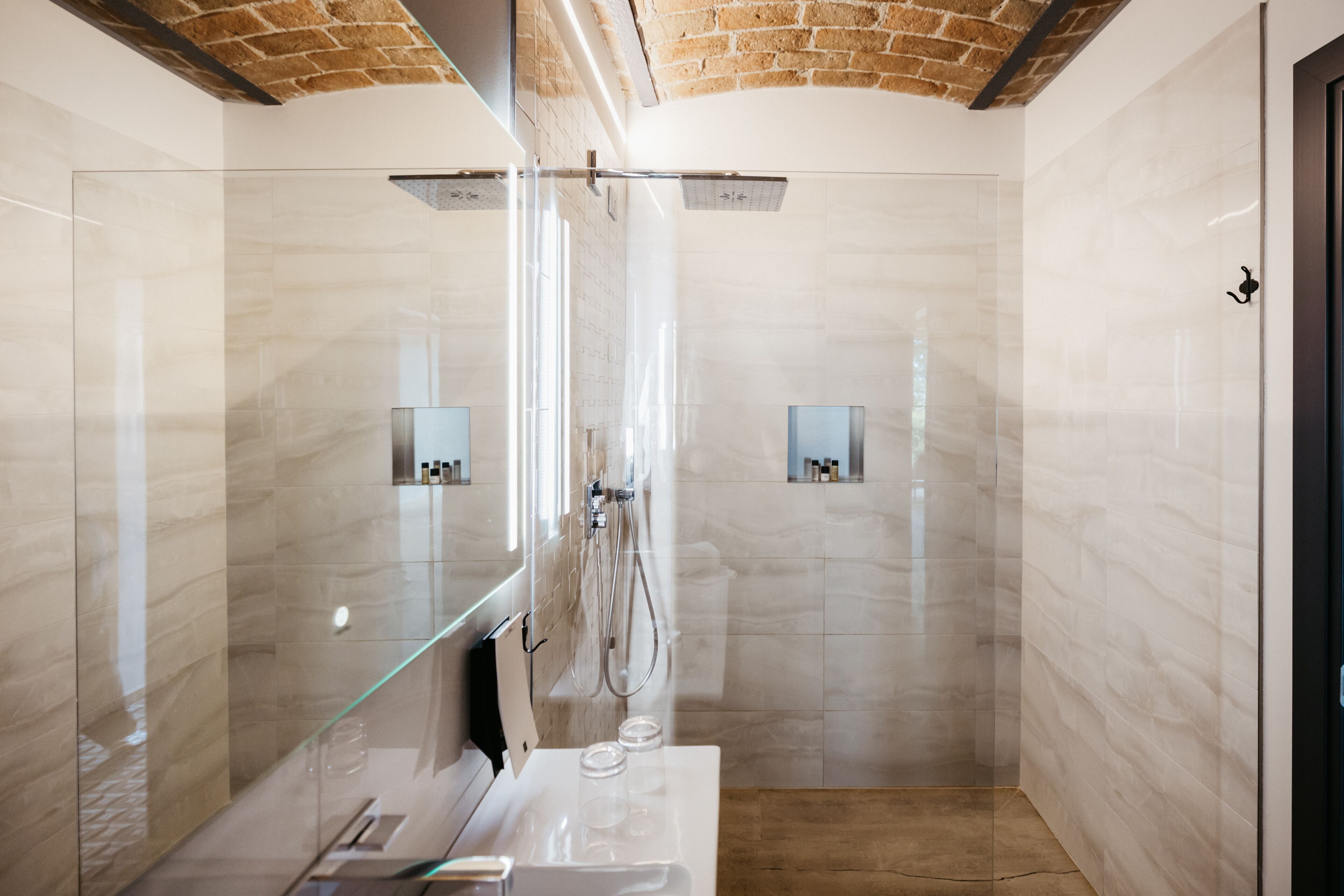Ein modernes Badezimmer mit einer gläsernen Duschkabine, Marmorwänden und einer Holzboden.