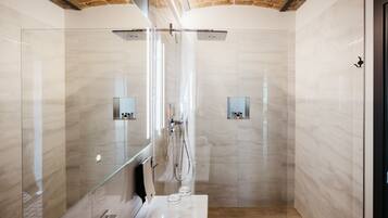 Ein modernes Badezimmer mit einer gläsernen Duschkabine, Marmorwänden und einer Holzboden.
