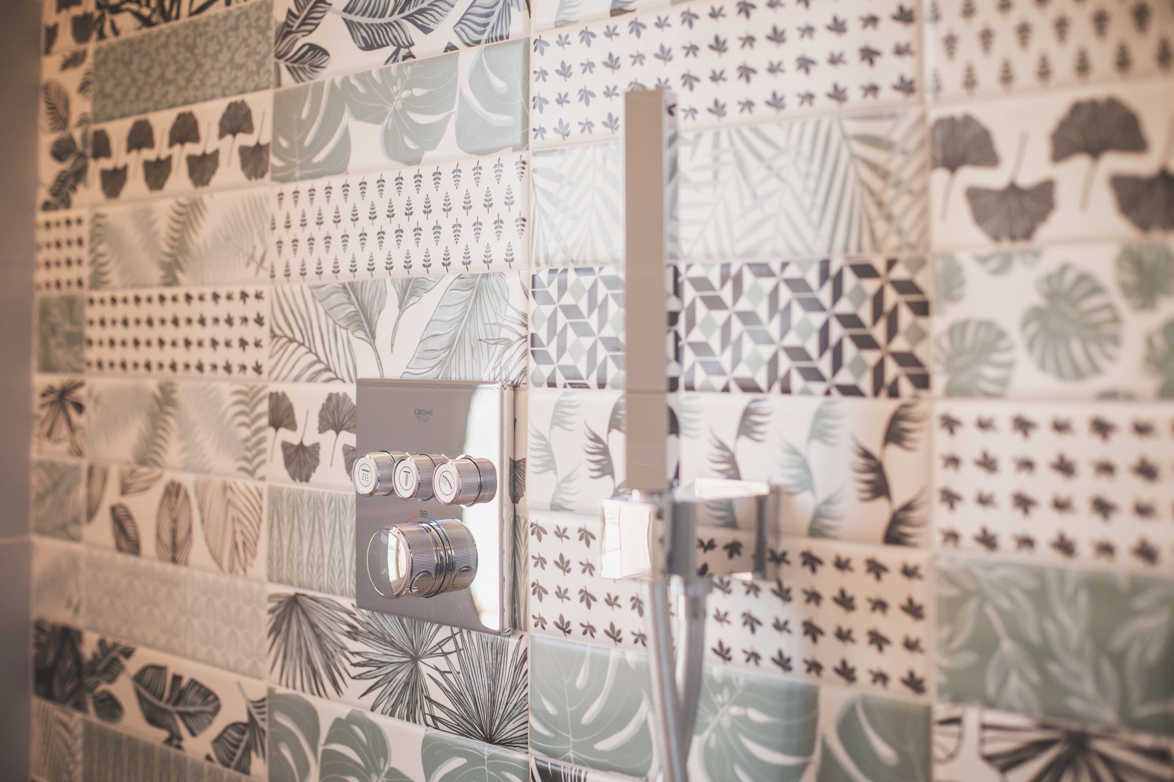 A wall with various patterned tiles, including tropical leaf designs and geometric shapes.