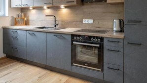 Una cocina moderna con armarios grises, un lavamanos de acero inoxidable y un horno empotrado.