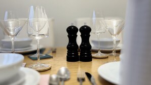 A dining table set with wine glasses, salt and pepper shakers, plates, cutlery, and a napkin. - Places to stay in Darlington with Free Parking (Darlington)