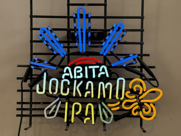 Une enseigne au néon avec l’inscription « ABITA JOCKAMO IPA » sur une structure métallique noire.
