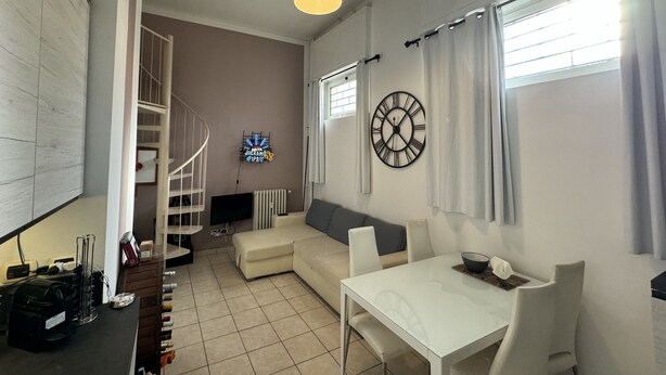 A modern living room with a white sofa, a dining table, and a staircase leading to an upper level. - Refuge of Lambrate - Milano Centrale (Milano)