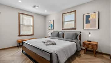 A modern bedroom with a bed, bedside tables, and artwork on the walls.