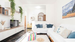Una sala de estar moderna con un sofá blanco, un televisor de pantalla plana y un cuadro en la pared.