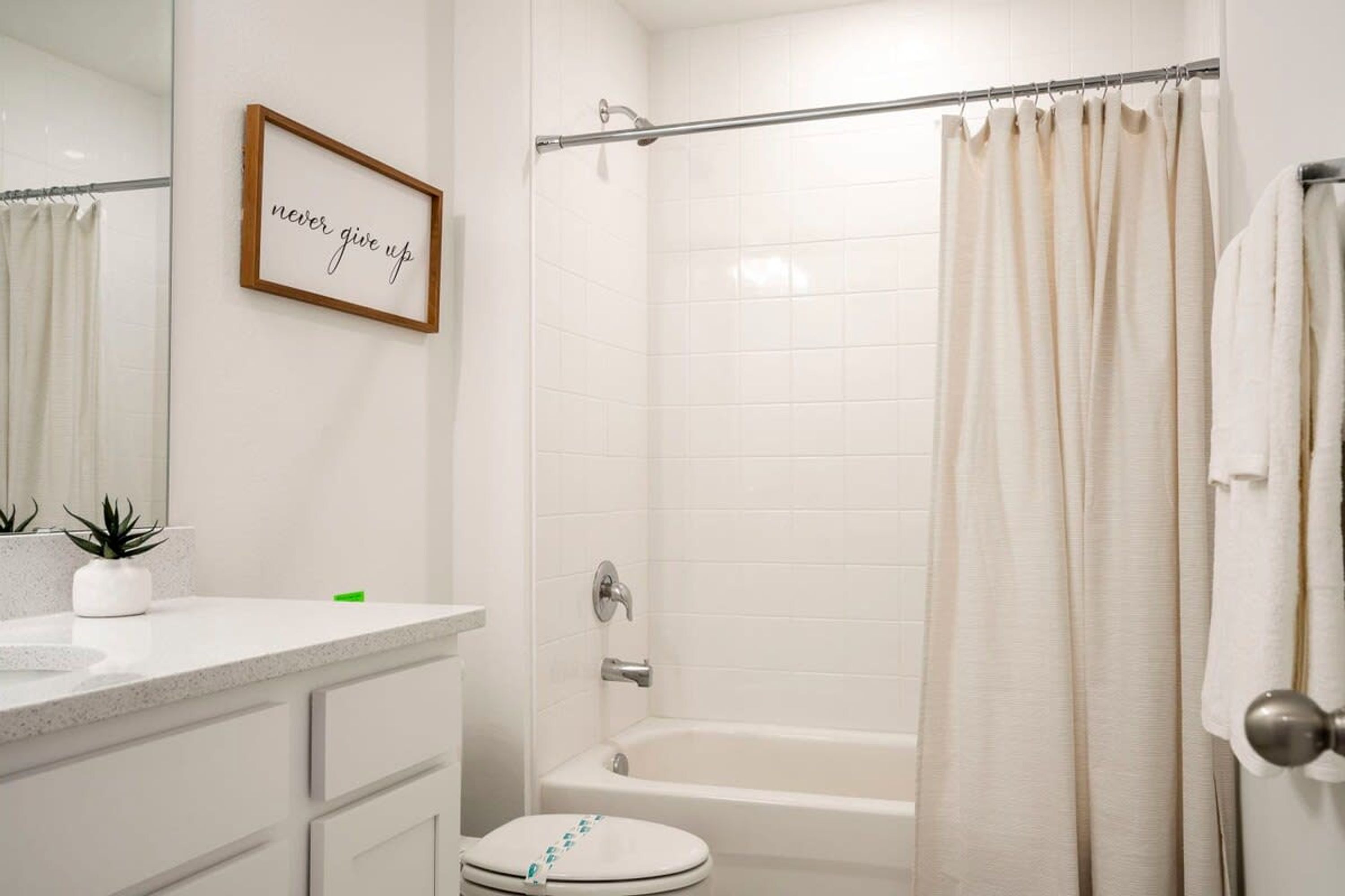 Une salle de bain avec une baignoire, des toilettes et une citation inspirante encadrée au mur.
