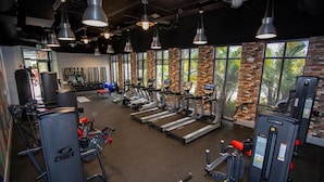 A gym with treadmills, weight machines, and a brick wall with large windows. - Cozy 3Bd Close to Disney Enclave 1021 (Davenport)