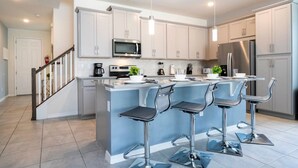 A modern kitchen with a central island, stainless steel appliances, and bar stools. - Splendid 5Bd w Pool at Solara Resort 2154 (Kissimmee)