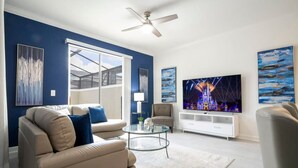 A modern living room with a beige sofa, a glass coffee table, and a flat-screen TV. - Fantastic 4 Bd w Pool at Storey Lake Resort 2709 (Kissimmee)
