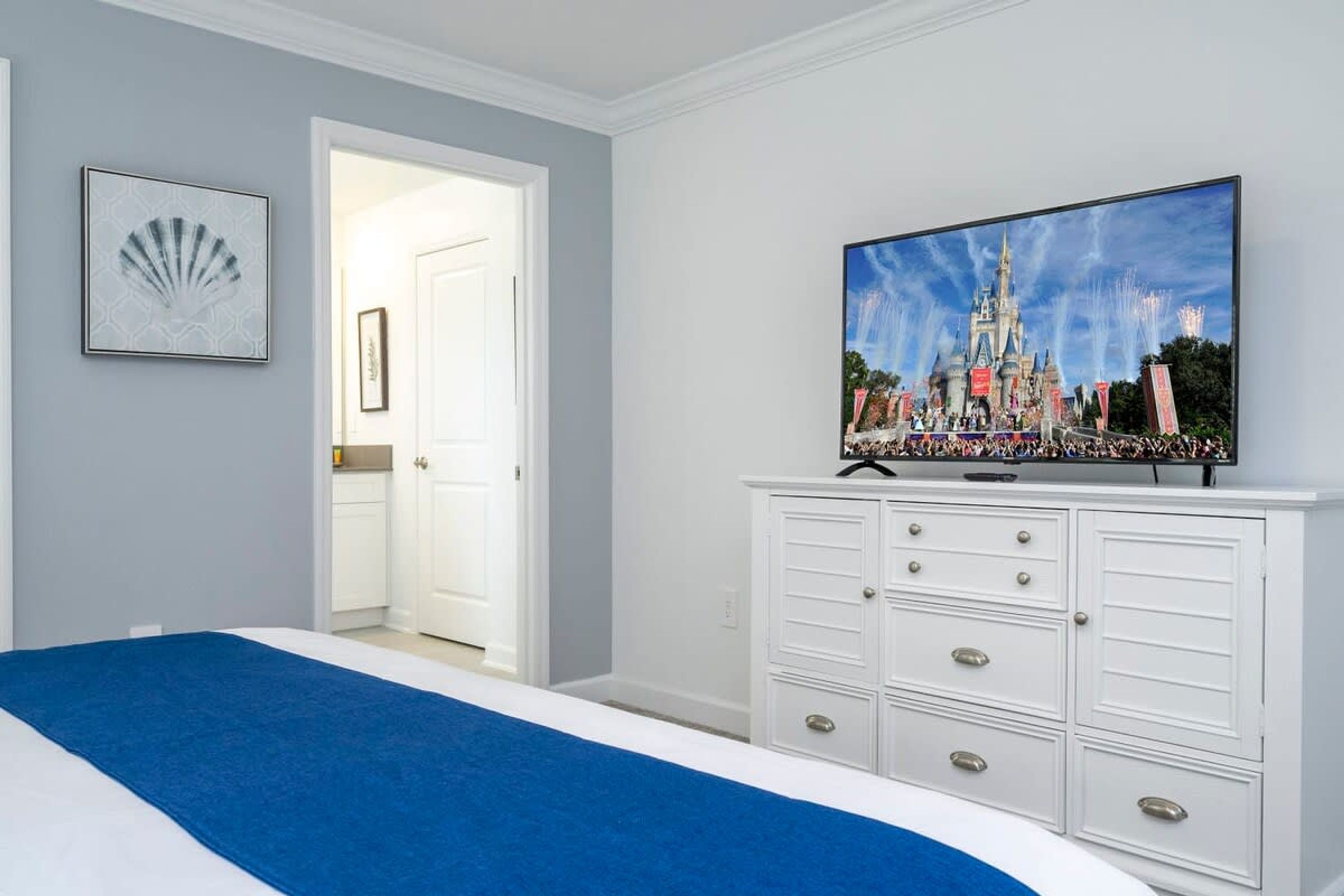 Une chambre d’hôtel avec un lit, un téléviseur posé sur une commode et une porte donnant sur une salle de bain.