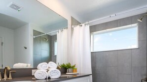 A modern bathroom with a large mirror, white cabinets, a bathtub, and a window. - Gorgeous 4 Bd w Pool Storey Lake Resort 2485 (Kissimmee)