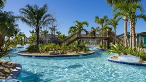 A pool area with palm trees, a rope bridge, and a small building in the background. - Gorgeous 4 Bd w Pool Storey Lake Resort 2485 (Kissimmee)