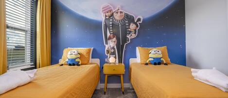 A bedroom with two beds, a mural of characters on the wall, and a window with curtains.