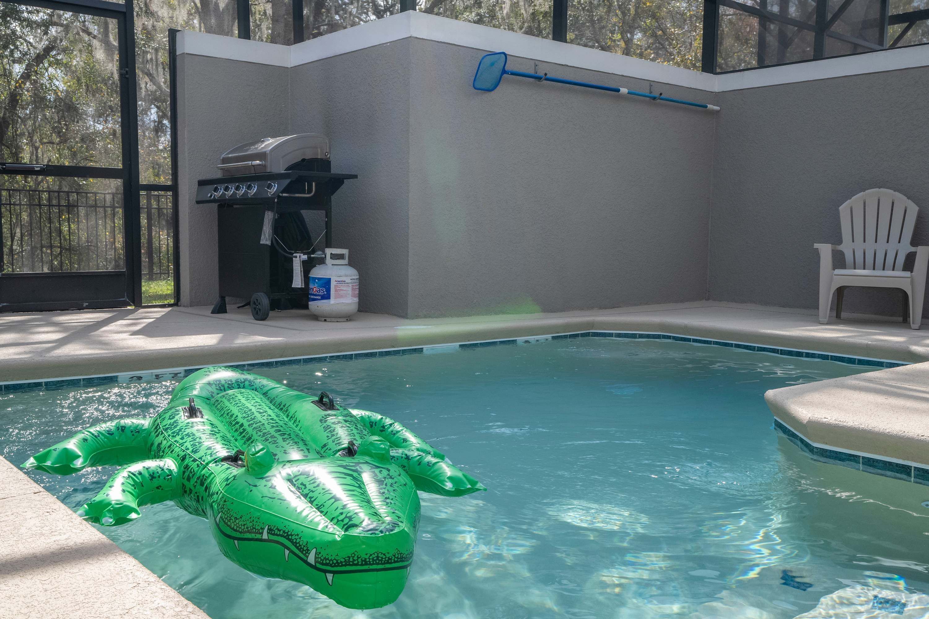 Una piscina con un juguete inflable de cocodrilo verde.