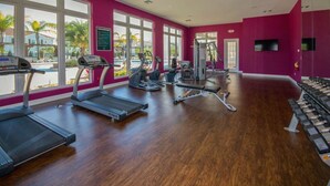 A gym with treadmills, elliptical machines, and weight benches, large windows with a view of palm trees and a pool. - Marvelous 4 Bd Close To Disney West Lucaya 8959 (Kissimmee)