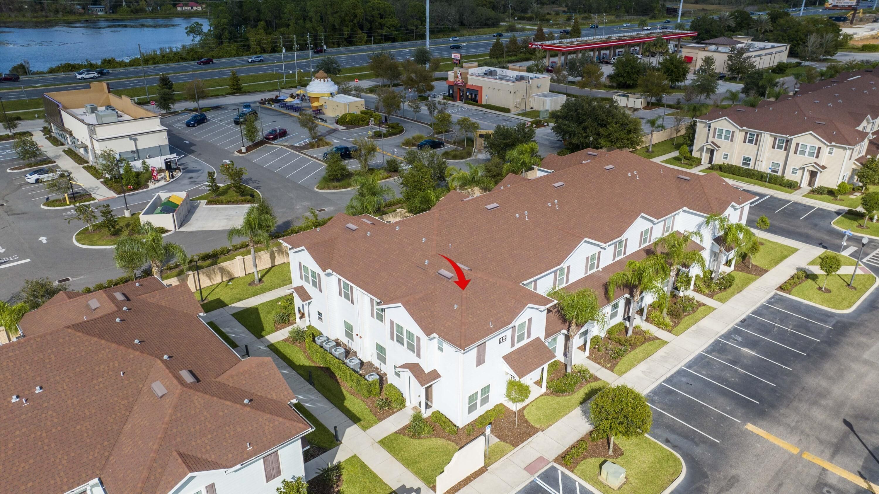 Vue aérienne d’un quartier résidentiel avec des maisons individuelles, une station-service et un parking.