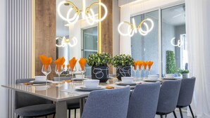 Un comedor moderno con una mesa larga, sillas tapizadas de gris e iluminación decorativa.