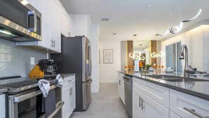 Una cocina moderna con electrodomésticos de acero inoxidable, una cafetera y una isla grande con fregadero.