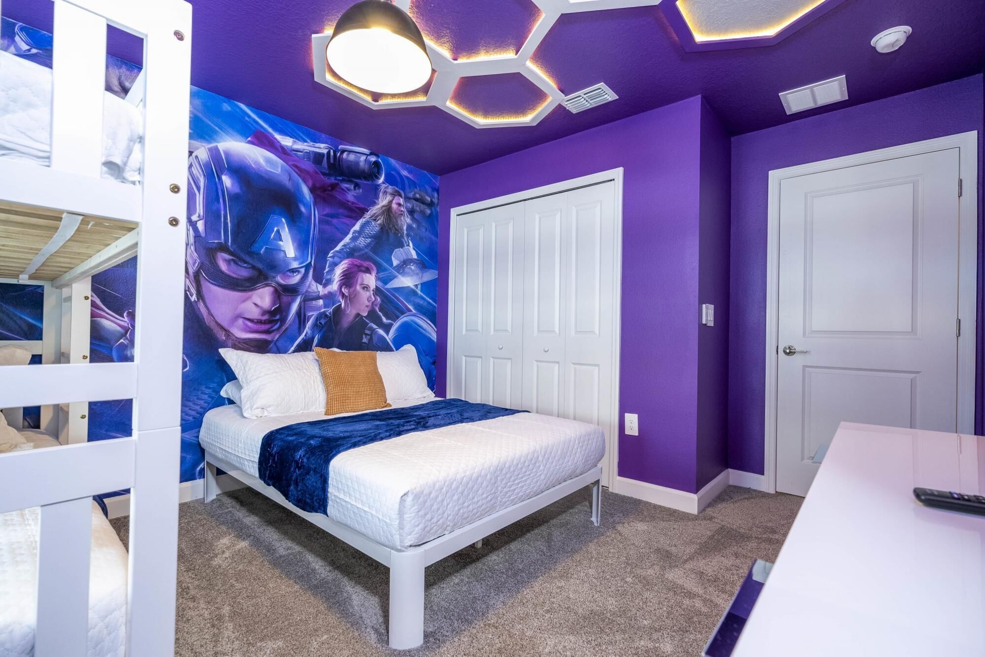 A bedroom with a bed, a mural, and a white wardrobe.