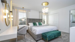 Un dormitorio moderno con una cama grande, mesitas de noche, un tocador y vistas al exterior.