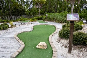 A miniature golf course with a green putting surface, a sand trap, and a wooden post with a sign indicating the hole number. - Charming 3Bd Close to Disney at Enclaves 745 (Davenport)