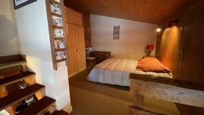 Un dormitorio con cama, armario de madera y una mesita.