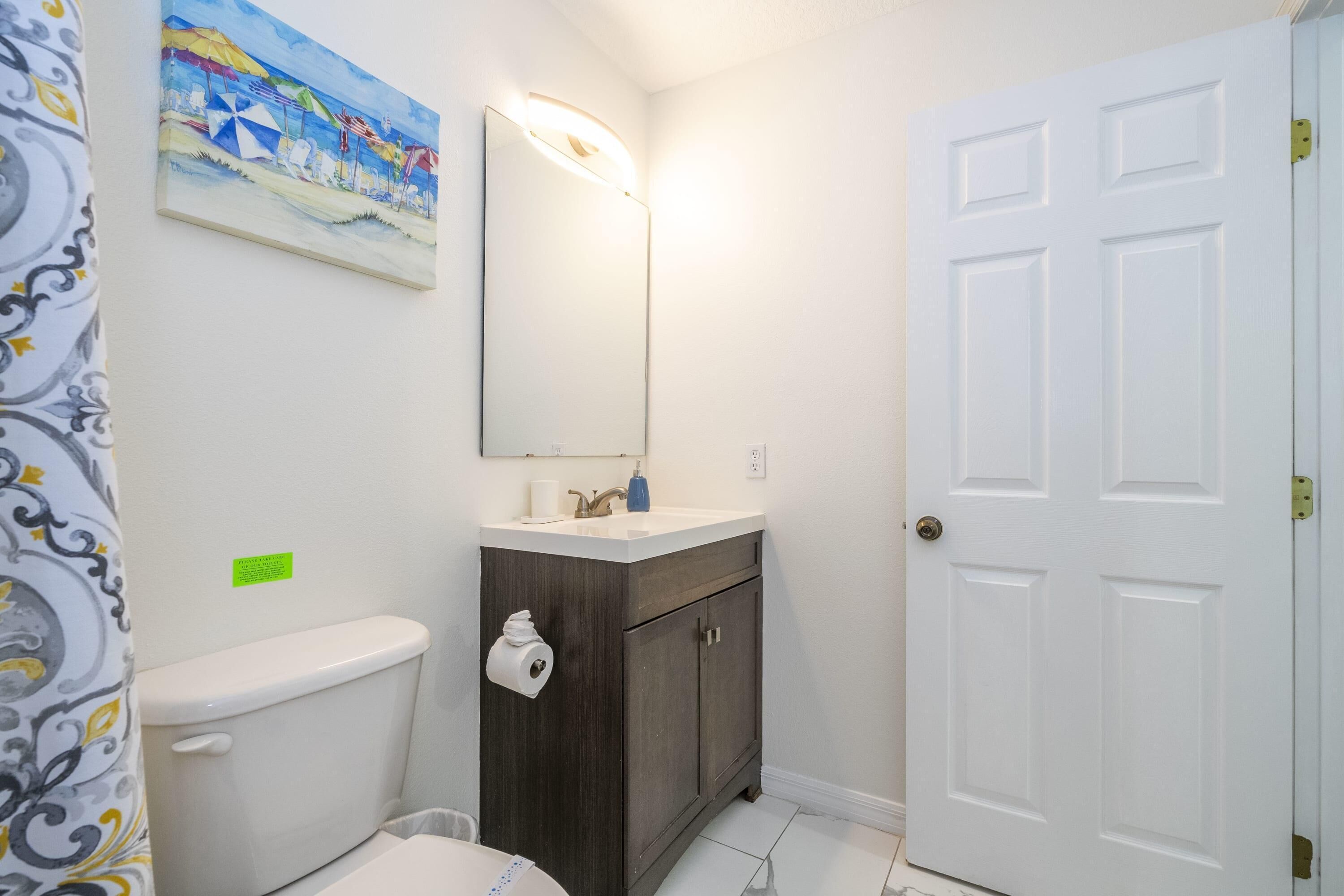 A bathroom with a toilet, sink, cabinet, and a door.