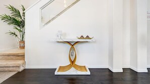 A staircase with a white wall, a marble console table with a golden base, and a potted plant. - Chic Vegas Retreat: Near Top Attractions (Las Vegas)