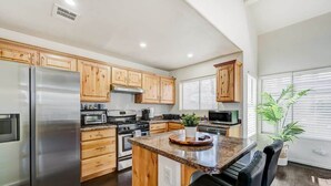 A kitchen with wooden cabinets, stainless steel appliances, a central island, and a potted plant. - Chic Vegas Retreat: Near Top Attractions (Las Vegas)