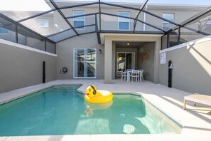 A swimming pool with a yellow inflatable duck, a covered patio area, and a dining table with chairs. - Stunning 5 Bd w Pool Storey Lake Resort 2653 (Kissimmee)