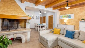 Un salon chaleureux avec une cheminée, un coin repas et un canapé agrémenté de coussins.