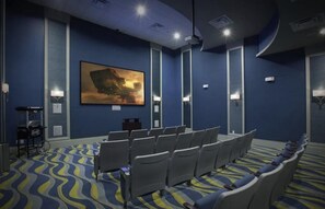 Une salle de conférence avec des rangées de chaises, un grand tableau au mur et un tapis à motifs.