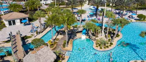 Un resort con una piscina grande, palmeras y una cabaña de techo de paja.
