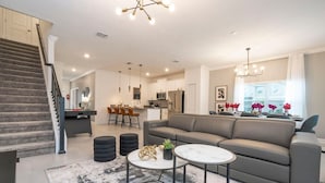A modern living room with a grey sofa, a round coffee table, and a staircase. - Stunning 4 Bd w Pool Storey Lake Resort 2400 (Kissimmee)