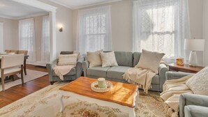 Una sala de estar con un sofá gris, una mesa de centro de madera y un tapete floral.
