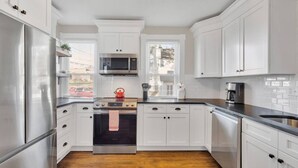 Una cocina moderna con armarios blancos, electrodomésticos de acero inoxidable y piso de madera.