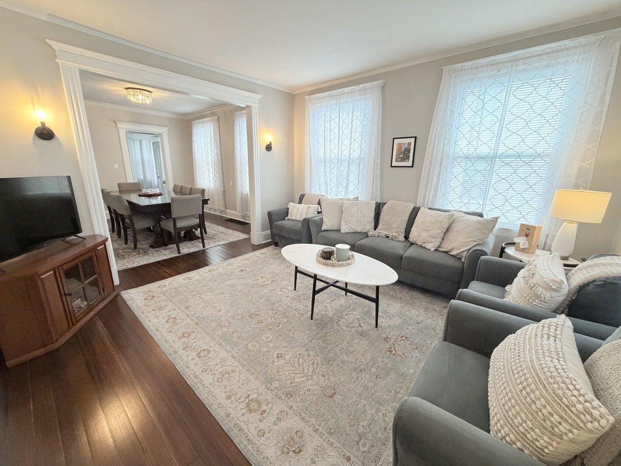 A living room with a sofa set, a coffee table, a TV, and a dining area with chairs and a table.