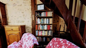 A room with a wooden bed, a bookshelf, and a wooden chair. - Cozy Cottage in Quiet Village with Nearby River- Access, Terrace, & Private Parking (Le Menoux)