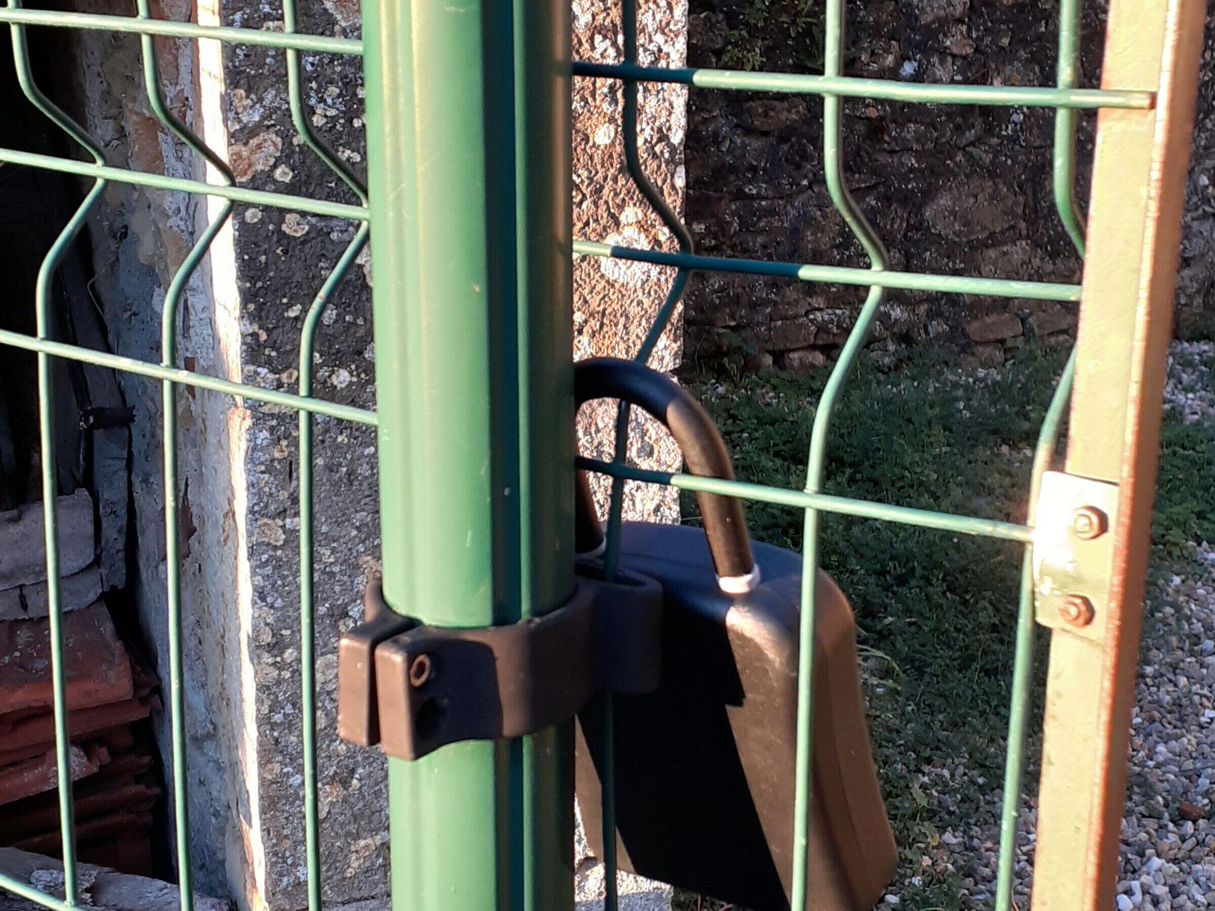 Une porte en métal avec un cadenas fixé à un poteau vert.
