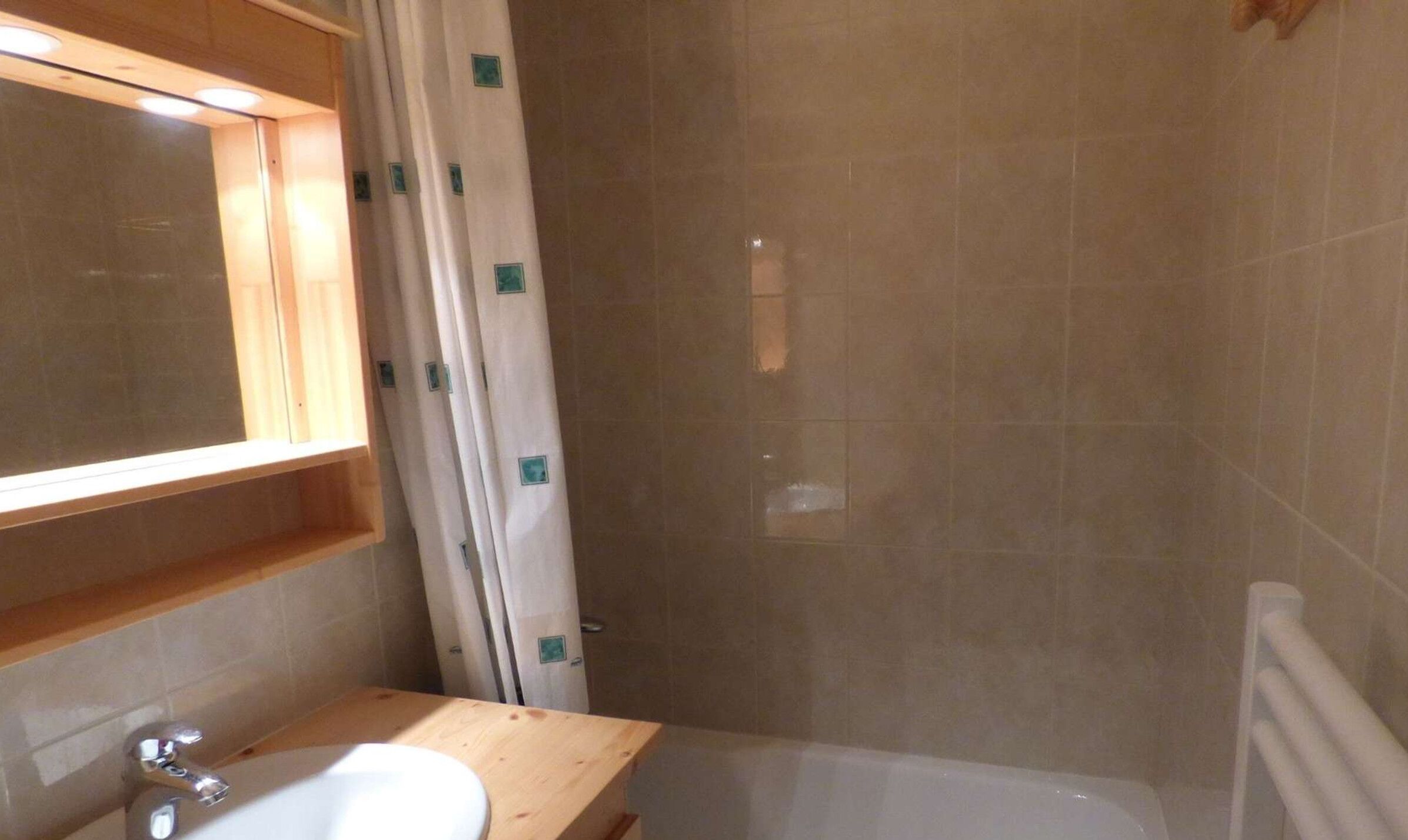 A bathroom with a wooden vanity, a sink, and a bathtub.