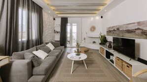 A modern living room with a grey sofa, a round coffee table, a flat-screen TV, and a stone accent wall. - Hidden Gem, 2Br Family Villa, with Sea View | Naxos Mikri Vigla Beach (Naxos)