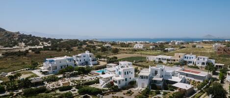 A coastal residential area with white buildings, a swimming pool, and a view of the sea.